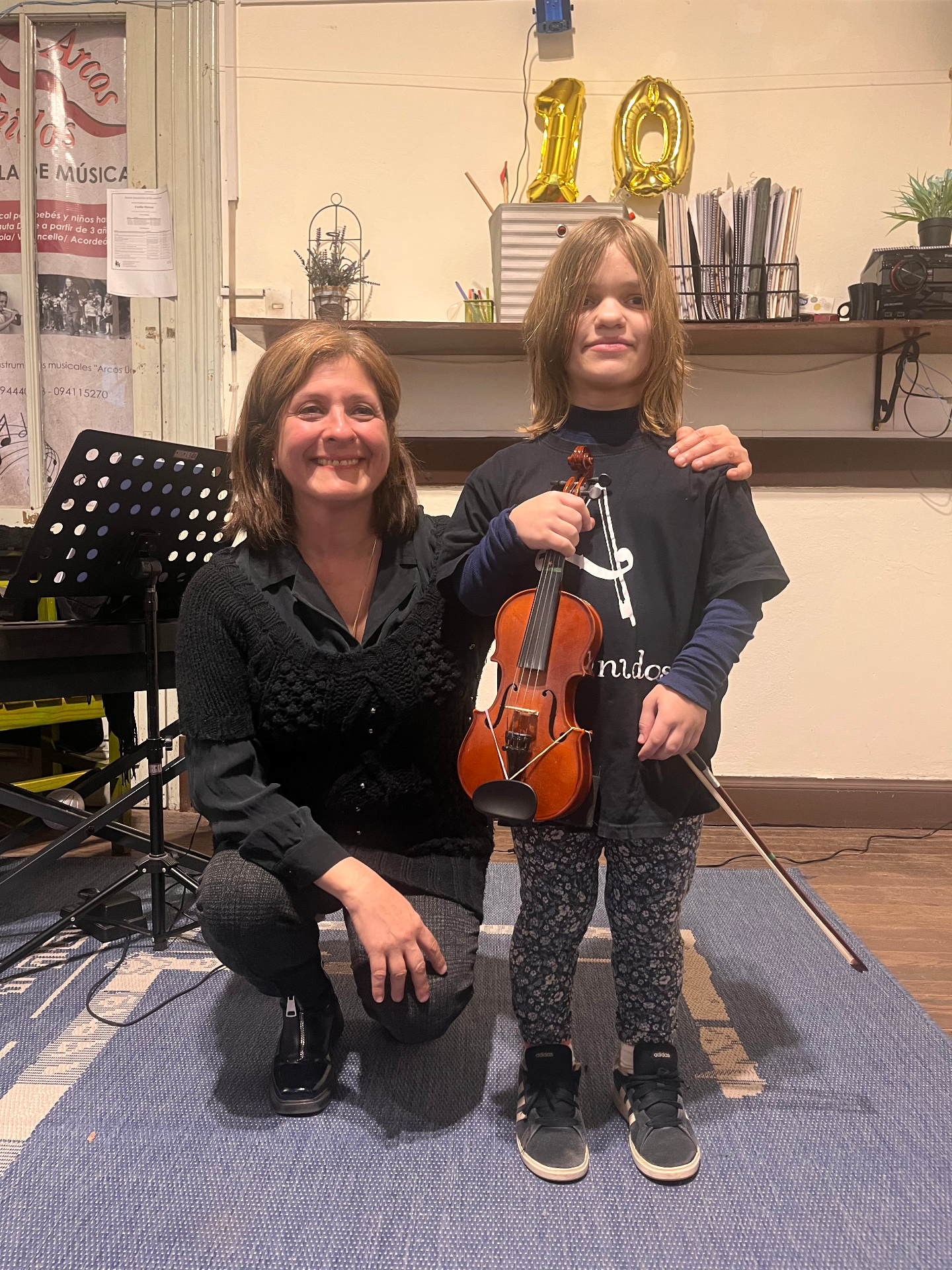 Profesora y alumna de violín celebrando los 10 años de Arcos Unidos